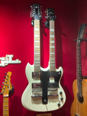 Kırmızı kadife arka plandaki üç elektro gitar diktir. Merkezi gitar, karmaşık tasarım, çoklu pikaplar ve kontrol düğmeleri ile açık renklidir. Gitar Kyiv, Ukrayna 06-19-2022
