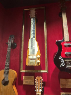Cam arkasında sergilenen çeşitli müzik enstrümanlarının koleksiyonu, gitar kipi Kyiv, Ukrayna 06-19-2022 ile çevrili, telleri ve perdeleri görünür olan akustik bir gitardır.