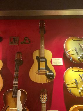 Akustik akustik gitarların bir koleksiyonu, tasarım ve renk açısından eşsiz, açık kahverengi g Kyiv, Ukrayna 06-19-2022 arka plan mağazasında dikey olarak sergilenmektedir.
