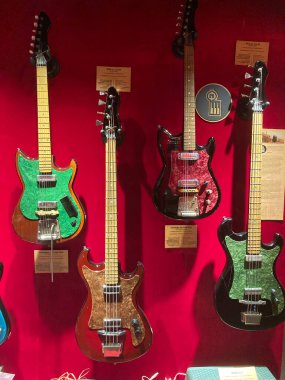 Kırmızı kadife arka plan üzerine monte edilmiş dört farklı elektro gitar koleksiyonu vücut rengi yeşil, turuncu, koyu kahverengi ve turuncu-yeşil blen Kyiv, Ukrayna 06-19-2022
