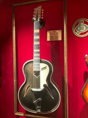 Kırmızı kadife kaplamalı akustik gitar, muhtemelen maun ya da siyah, f-delik ses delikleri, yankesicilik, üstüne etiket, Kyiv açısı, Ukrayna 06-19-2022