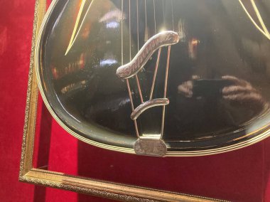 Elinde flaşlı akıllı telefon tutan kişi, sıcak ışıklı odada kırmızı halılı yerde altın gitar yakalayan kişi, muhtemelen bir sergi ya da gösteri alanı Kyiv, Ukrayna 06-19-2022
