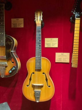 Ayrı mekanlarda sergilenen müzik aletleri olan kırmızı halılı zemin çoğunlukla dik piyano ve gitarlarla, Kyiv, Ukrayna 06-19-2022 kimlik tespiti için tahta pankartlar.