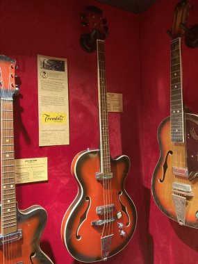 Bir museumexhibition ayarında koyu kırmızı arka planda tarihi veya sanatsal gitarların görüntülenmesi her gitar yumuşak, üstten aydınlatma ve smal Kyiv, Ukrayna 06-19-2022 ile izole edilmiştir.