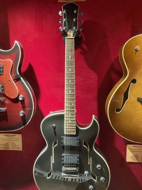 Kırmızı gradyan arka planına karşı klasik elektro gitar, yarı içi boş veya içi boş vücut yapısı, iki pikap, yankesici, gergin teller, frettin Kyiv, Ukrayna 06-19-2022