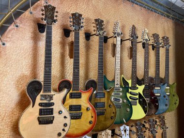 Duvarda çeşitli renklerde elektro gitarların ve tasarımların dikey görüntüsü, muhtemelen kapalı bir müzik mağazası veya toplama odası Gölgeler Kyiv, Ukrayna 06-19-2022 'yi gösteriyor