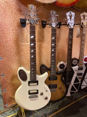 Turuncu bir halıya yerleştirilmiş renkli gitarlardan oluşan bir grup, her biri görünür ayar çivileri ile doğal ışık altında samimi bir şekilde sunuluyor: Kyiv, Ukrayna 06-19-2022
