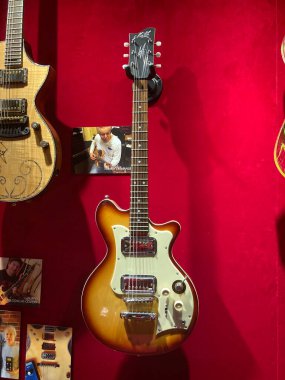 Kırmızı kadife arka plan ve beyaz merkez gitara karşı sergilenen üç gitarlı bir koleksiyon, yankesicisi Kyiv, Ukrayna 06-19-2022 ile klasik elektrikli Gibson.
