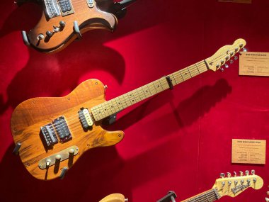 Sergilenen elektro gitar koleksiyonunun yakın çekimi, ağırlıklı olarak ahşap, ön planda kırmızı bir gitar, boynu yukarıya dönük diğer gitarlar Kyiv, Ukrayna 06-19-2022