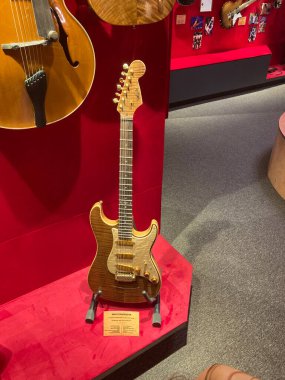Müze sergisindeki ahşap akustik gitarın yakın çekimi, sicimler ve fretboard ile görülebilen bir arka plan. Kısmen görülen başka bir enstrüman. İnsan yok ya da Kyiv, Ukrayna 06-19-2022