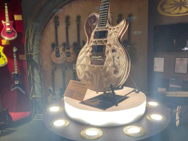 Sarı ışıklı dairesel ayakta duran tahta gitar heykeli, duvar destekli gerçek gitarların zemininde sergileniyor Wa Kyiv, Ukrayna 06-19-2022 tarafından vurgulanan ayrıntılı işçilik