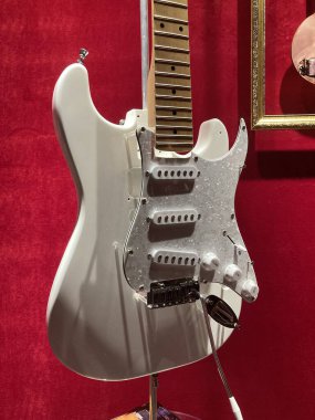 Beyaz Fender tarzı elektro gitarın yakın çekimi, pikaplar, akort mandalları, perdeler ve seçici anahtar parçaları görünür, bulanık, sıcak ışıklandırılmış Kyiv, Ukrayna 06-19-2022