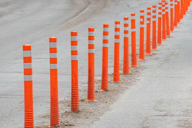 Yıpranmış bir yol yüzeyine dizilmiş turuncu trafik konileri, gün ışığında sürücü spedestrianscylistleri için bir alanı veya sınırı işaretliyor.