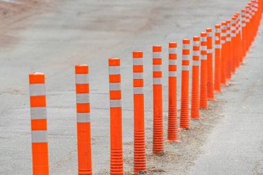 Beton kaldırım ya da patika üzerinde yansıtıcı çizgileri olan turuncu güvenlik konileri..