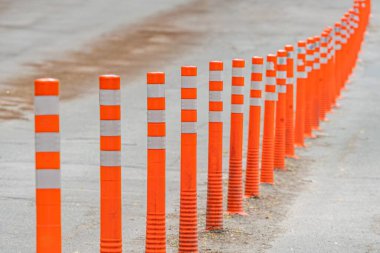 Trafik kontrolü veya yarı u 'da yaya güvenliği için ön tarafa doğru eğimli bir çizgide sıralanmış, asfalt yol kenarı veya patika boyunca yansıtıcı turuncu güvenlik konileri.