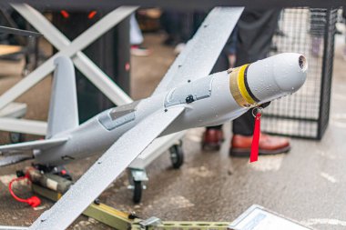 Metalik sanayi zeminine karşı yerleştirilmiş sarı ve kırmızı işaretli gri ve beyaz bir dronun kapalı ekran görüntüsü açılı perspektifli üç boyutlu