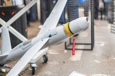 Metalik sanayi zeminine karşı yerleştirilmiş sarı ve kırmızı işaretli gri ve beyaz bir dronun kapalı ekran görüntüsü açılı perspektifli üç boyutlu
