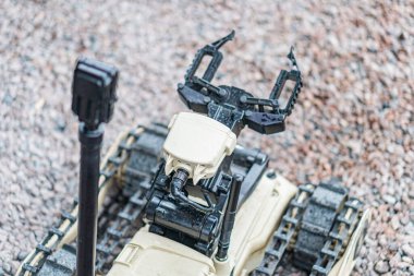 Bir robotik keşif aracı dış yüzeyde çoklu uzuvlar, kamera ya da sensör cihazıyla donatılmış bir şekilde gösterilir. Robotun engebeli bir tasarımı, gri-kahverengi renk düzeni ve endüstriyel görünümü vardır.