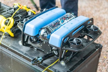 Su altı keşif aracı, mavi pervaneler, hareket halinde ya da hazırlık, kablolar, güç kaynağı kontrol sistemi, siyah giysili kişi, açık alan sert yüzey, kapalı ya da kapalı gün