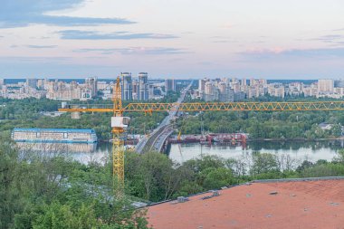 Büyük bir su, tekne, inşaat vinci, apartman binaları, ticari yapılar ve hatta hafif ışıklandırma ile Kiev 'in bulutlu kentsel manzarası kıyıdan ayrıldı.