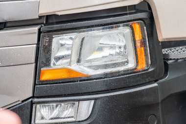 Ön sağ taraftaki siyah kamyonların yakın görüntüsü, far montajına ve kaputla küçük hizalama sorununa odaklanıyor. Ön far ağırlıklı olarak beyaz, birden fazla ampul ve yanmamış bir ışık içeriyor.
