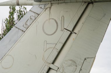 Gri metal alaşımlı ya da titanyumdan yapılmış eski bir uçak motoru ve kanat kökünün yakın çekim görüntüsü. Bakım işaretleri ve yıpranmış görünüm ışık altında bile