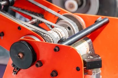 Bir montajda birbirine bağlı dişli ve şaftlı, turuncu endüstriyel robot kolunun yakın görüntüsü, endüstriyel bir ortamda standart bir fotoğrafta yakalanır.