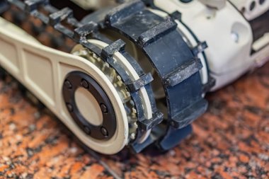 Gri ve beyaz bir robotik cihazın hareketler veya etkileşim için tasarlanmış düzgün olmayan bir yüzey üzerindeki yakın görüntüsü Eklem veya eklenti noktası görünür