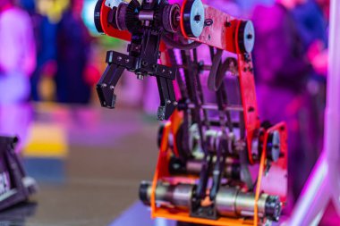 Profesyonel bir arka planda aktif, kırmızı çoklu eksenli robotik kolun kapalı görüntüsü, robotun merkez denek olarak açılı perspektifi ve belirsiz makineler içerir.