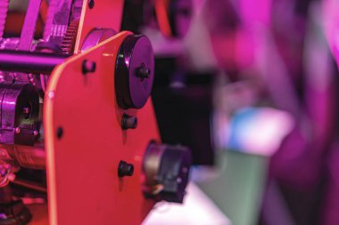 Kırmızı mekanik robot koluna yakın plan, işlevsel vitesli metalden yapılmış, muhtemelen bir atölye, mor ışık altında, hiçbir insan ya da hayvan mevcut değil doku ve renk odaklı fotoğraf