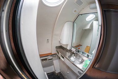Beyaz, kullanışlı bir uçağın iç yüzeyinin yakın görüntüsü hafif kıvrımlı bir pencere ya da pencere boyunca iki lavabo, üstlerindeki küçük aynalar, bir tarafta duvara monte edilmiş bir yapı ve...