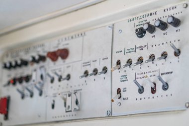 Görüntü, bir uçak kabininde dairesel göstergeler, göstergeler, düğmeler ve düğmeler içeren bir çift elektronik kontrol panelini gösteriyor. Paneller kırmızı aksanlı beyaz ya da bej.