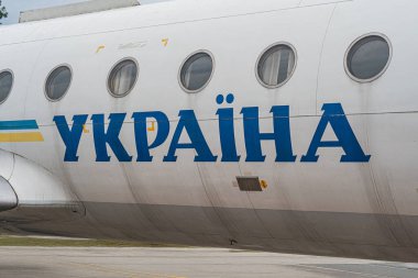 UKRAINA beyaz ve mavi bir Ukrayna uçağının kapalı pencereli ve yolcu olmayan bir açıyla görüldüğü bir pist veya taksiyoldaki yakın çekimi