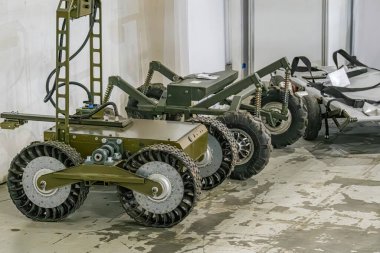 Bir atölye resmi iki yeşil-gri askeri mini robot gösteriyor, muhtemelen havacılıkla ilgili. Kurgu, yapay ışıklandırma, döküm gölgeleri olan beton döşemeli bir atölye. Makineler...