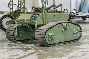 Yeşil bir arazi resmi, Ukrayna askeri engebeli mini robot UGV tırtıl rayları, kapalı alan beton ayarı, potansiyel askeri veya endüstriyel kullanım, sağlam yapı, nötr perspektif