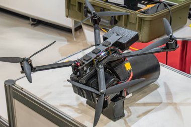 Siyah kuadkopter drone 'un kapalı çekimleri, muhtemelen bir atölye ya da sergi salonunda diğer objeler arasında yeşil plastik sandık ve elektronik aydınlatma koşulları vardır.