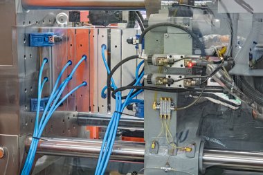 Sanayi sahnesi, büyük ihtimalle seri üretim için kullanılan N tipi bir fabrika ortamında klempleme mekanizmaları, hidrolik bileşenler, mavi kablolar ve sarı borular içeren büyük bir metal matbaayı gösteriyor.