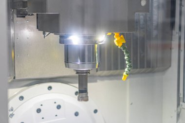 Endüstriyel ortamda çalışan bir işletim makinesinin yakın görüntüsü, metal silindirik bileşenli makine parçaları görünür durumda, dişliler, kollar ve kesme araçları dahil.