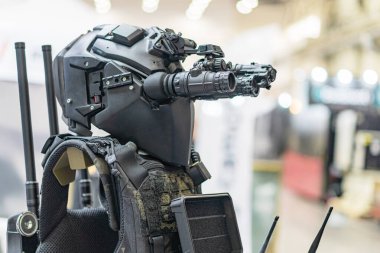 Askeri zırh giyen, kask, yelek, eldiven ve bot giyen birçok insanın katmanlı kompozit görüntüsü sanayiden karanlık odalara ve dış mekanlara kadar değişkenlik göstermektedir.