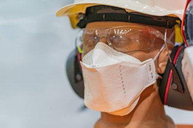 Laboratuvar ya da tıbbi ortam gibi steril ya da maruz kalma korumalı bir ortamda kişisel koruma ekipmanı PPE kullanan bir kişi tam vücut kıyafeti, cerrahi maske ve kask giyer.