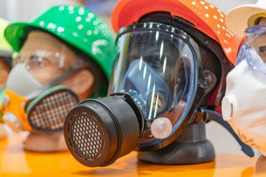 Turuncu renkli düz bir yüzeye yerleştirilmiş çeşitli solunum cihazlarının toplanması, açık görünürlük için Respirator türleri tam yüz ve burun modelleri, bazıları filtreli t