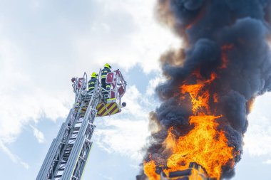 Açık havada gündüz yapılan yangın operasyonunun kolaj görüntüsü, kırmızı merdiven kamyonu ve yakın plan ateşli patlama siyah duman, dramatik kontrast