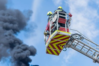İtfaiye aracı kaldırma, acil müdahale, itfaiyeciler, tam teçhizat, merdiven, duman, beyaz kamyon, kırmızı işaretler gün ışığı, doğal ışık yoğunluğunda yangın