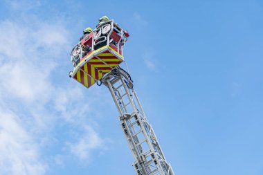 Endüstriyel vinç kırmızı, düşey pozisyonda geniş yelkenli yelkeni var. Vinçte ağır işaretler var. Bulutlu bir gün, dağınık bulutlar ve mavi gökyüzü.