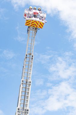 Gökyüzü İtfaiye Merdiveni beyaz, camları açık ve acil durum ışıkları kapalı bir araç. Görüntünün ötesinde herhangi bir içerik ya da tanımlanabilir nesne yok. Yükseklik ve fayda vurgusu..