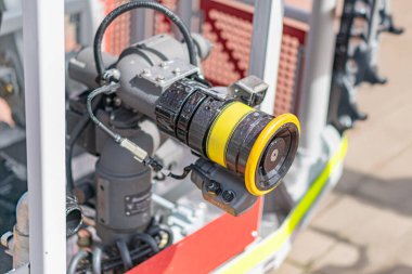 Endüstriyel makinelere monte edilmiş, muhtemelen güç üretimi veya altyapıyla ilgili büyük, sarı ve siyah bir güvenlik kamerası var.