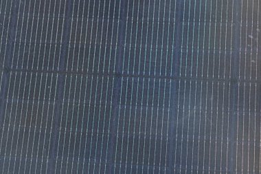 Büyük bir açık hava yapısının düşük açılı fotoğrafı koyu dikey parmaklıklar, ağ dokusu ve daha açık yüzeyi muhtemelen bir çit ya da bölme aydınlatması öğleden sonra geç saatlerde metin haliyle