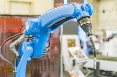 Endüstriyel bir robot, ağırlıklı olarak mavi, kırmızı ve beyaz uçak gövdesi üzerinde çalışıyor. Robotun birden fazla eklemli kolu var. Diğer gövde bölümleri de görülebilir.