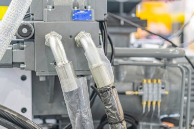 Metalik kaplama, silindirik borular, borular, borular, kapalı bir kanal, nötr renk paleti ortamına yakın, büyük bir endüstriyel makine parçasının yukarıdan görünüşü.