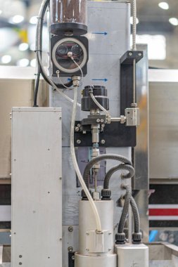 Endüstriyel bir ortamda endüstriyel robot ağırlıklı olarak metalik makineler, vanalar, tüpler ve göstergeler yan taraftaki beton arka plan kontrol paneline karşı, üstten gelen gölgeli aydınlatma